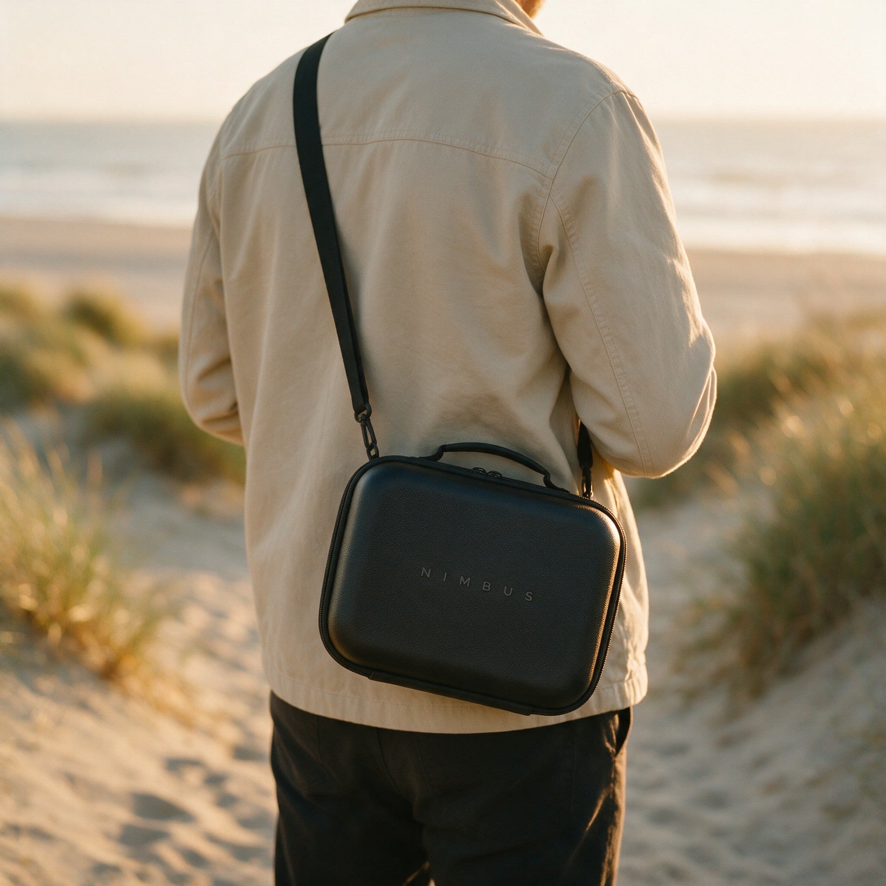 Sac de transport NIMBUS noir porte en bandouliere sur un sentier cotier